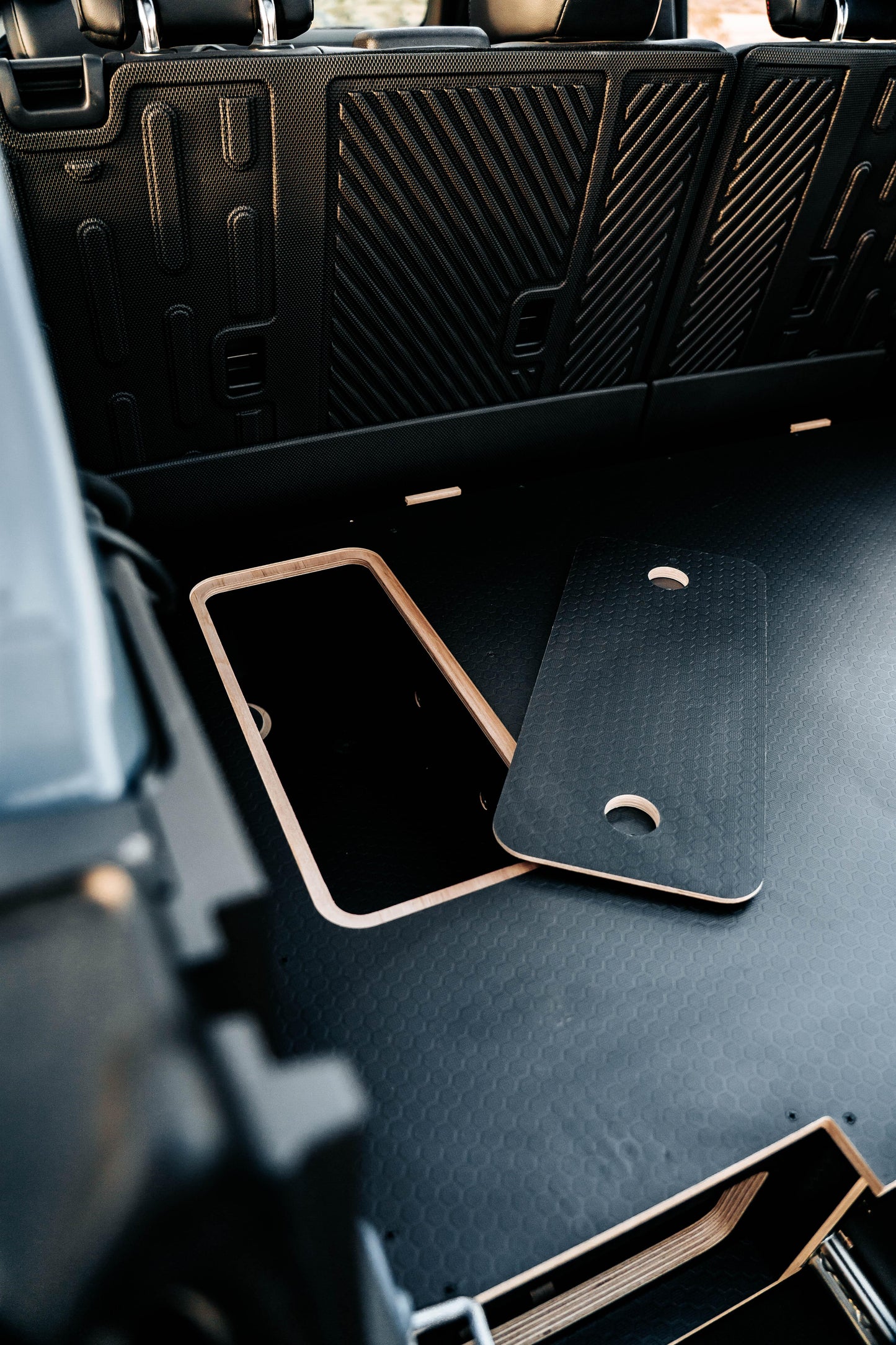 Vehicle trunk storage compartment with removable wood panel and hex pattern surface