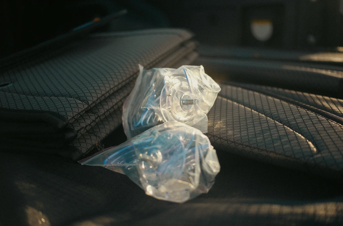 Overlanding storage hardware in plastic bags on textured cargo mat, ready for adventure setup