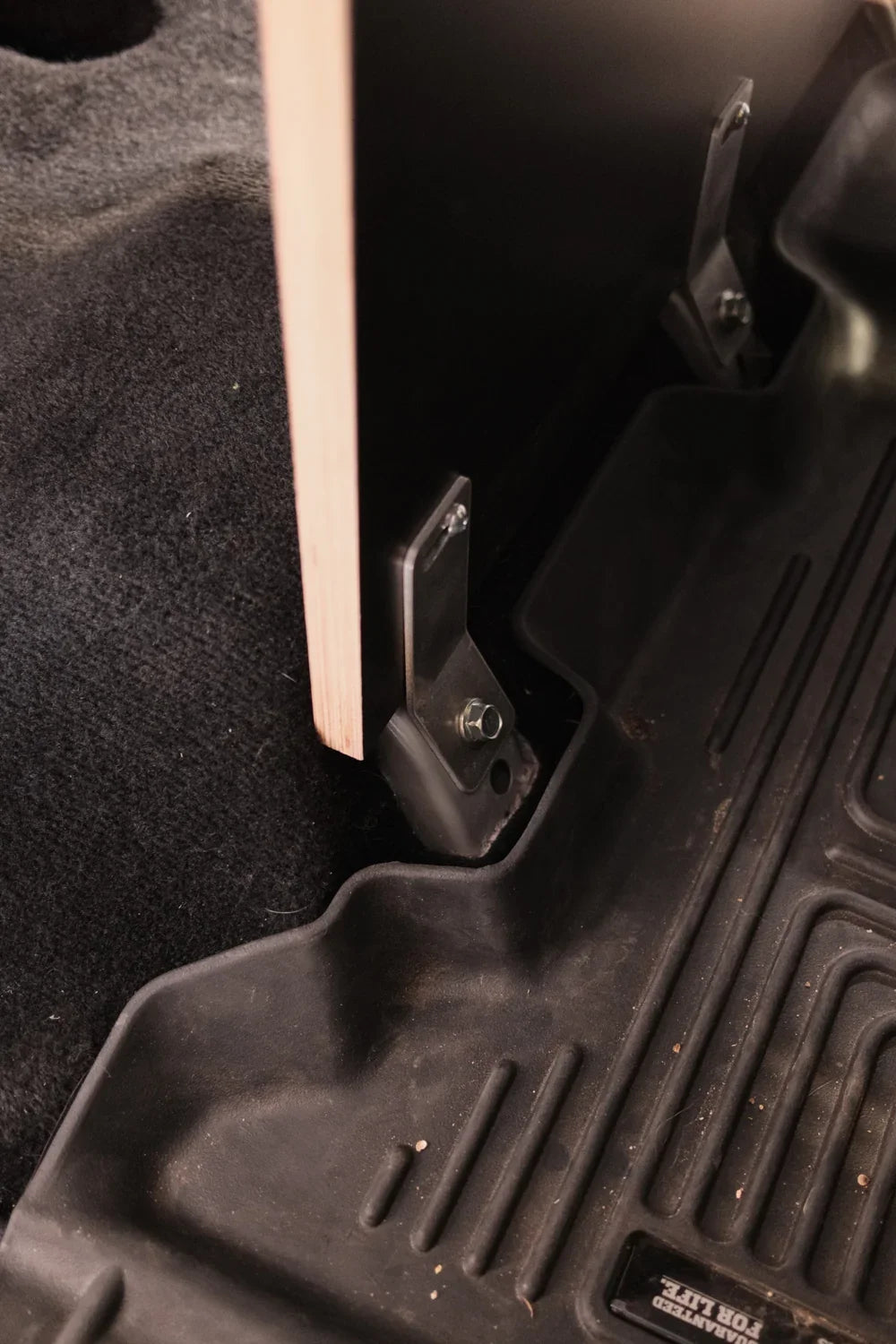 Solid wood storage solution mounted in vehicle with metal brackets and black floor mat