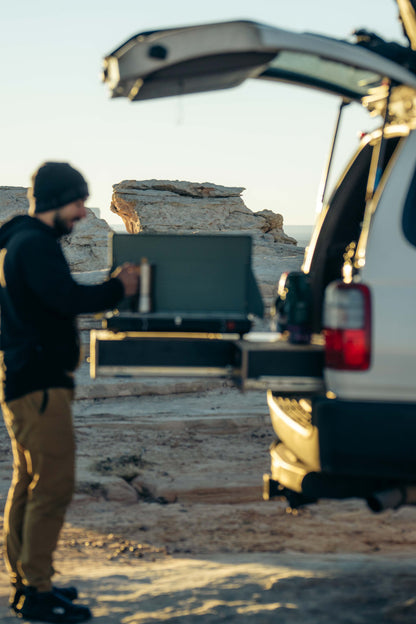 Man using vehicle drawer storage system outdoors at rocky campsite