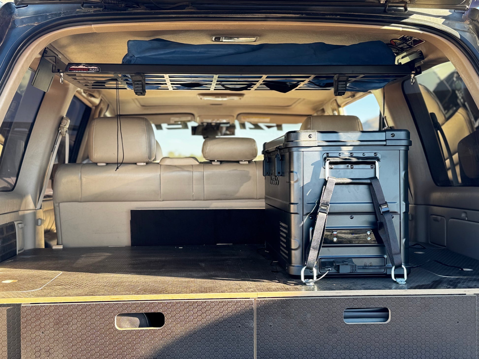 SUV rear cargo space with storage drawers, roof rack and large portable fridge