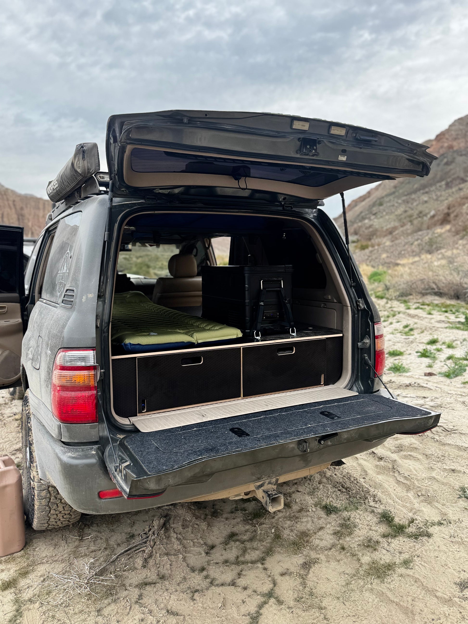 SUV with open tailgate showing custom wood drawer storage system for vehicle organization outdoors