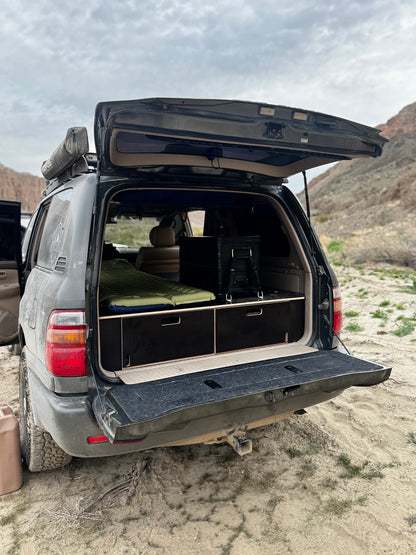 SUV with open tailgate showing custom wood drawer storage system for vehicle organization outdoors