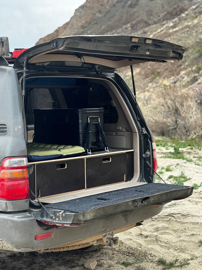 SUV with custom wooden drawer storage system and camping gear in the trunk outdoors