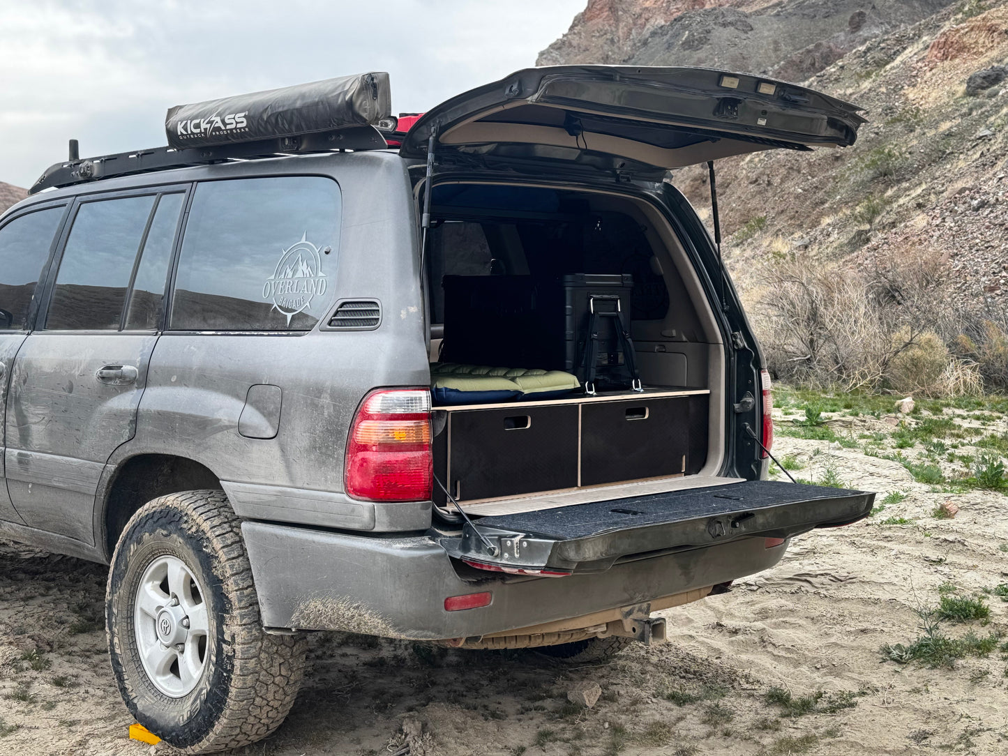SUV with custom wooden storage drawers and camping gear in desert landscape