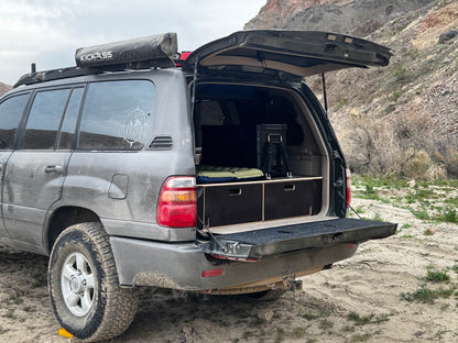 SUV with custom wooden storage drawers and camping gear in desert landscape