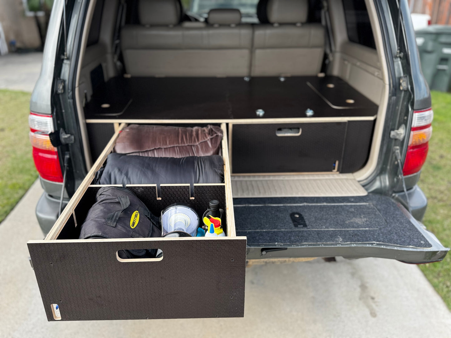SUV with custom wood cargo drawer system, organized for vehicle storage and camping gear