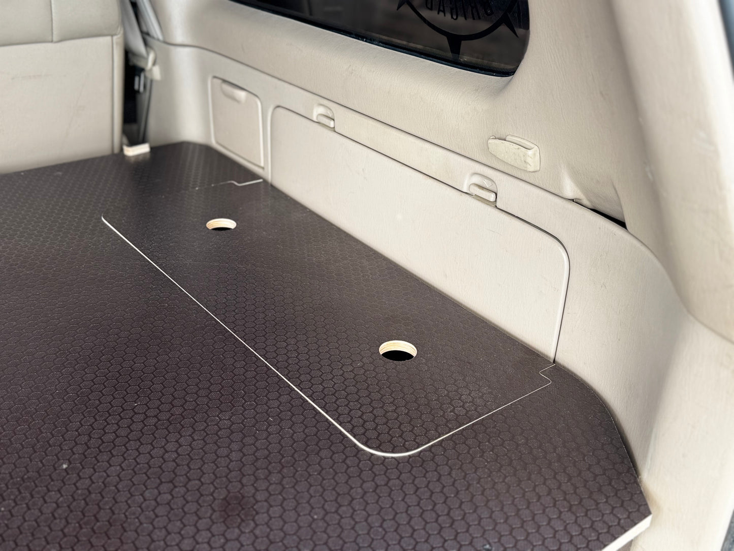 Custom wood cargo storage platform with access holes in SUV trunk