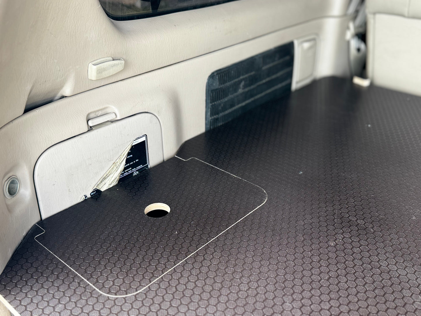 Vehicle cargo area with custom hex-pattern storage platform and built-in access hatch