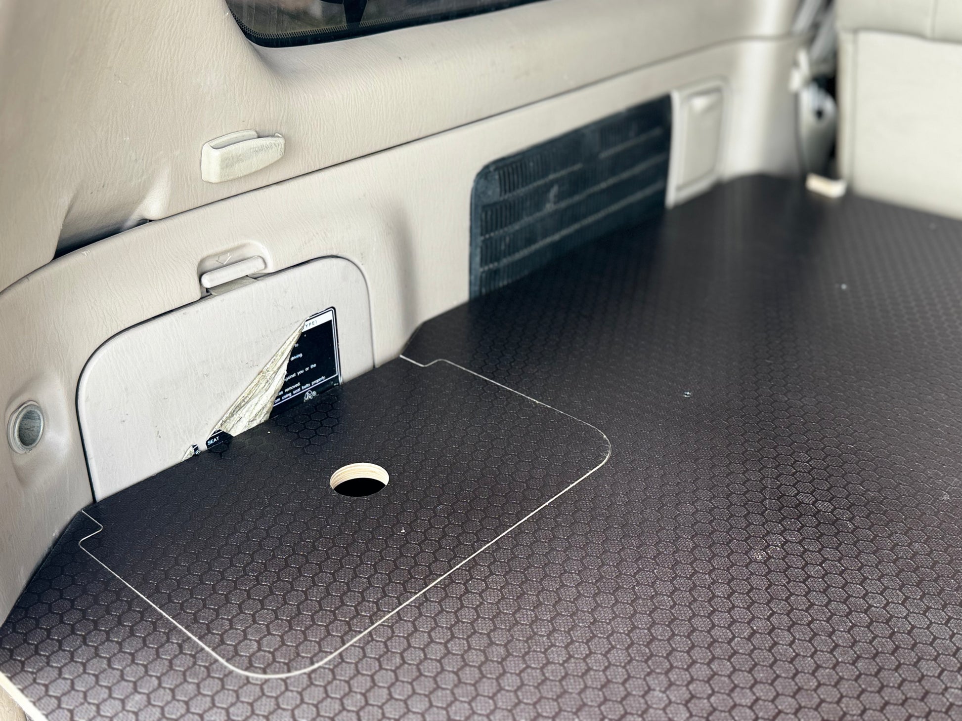 Vehicle cargo area with custom hex-pattern storage platform and built-in access hatch