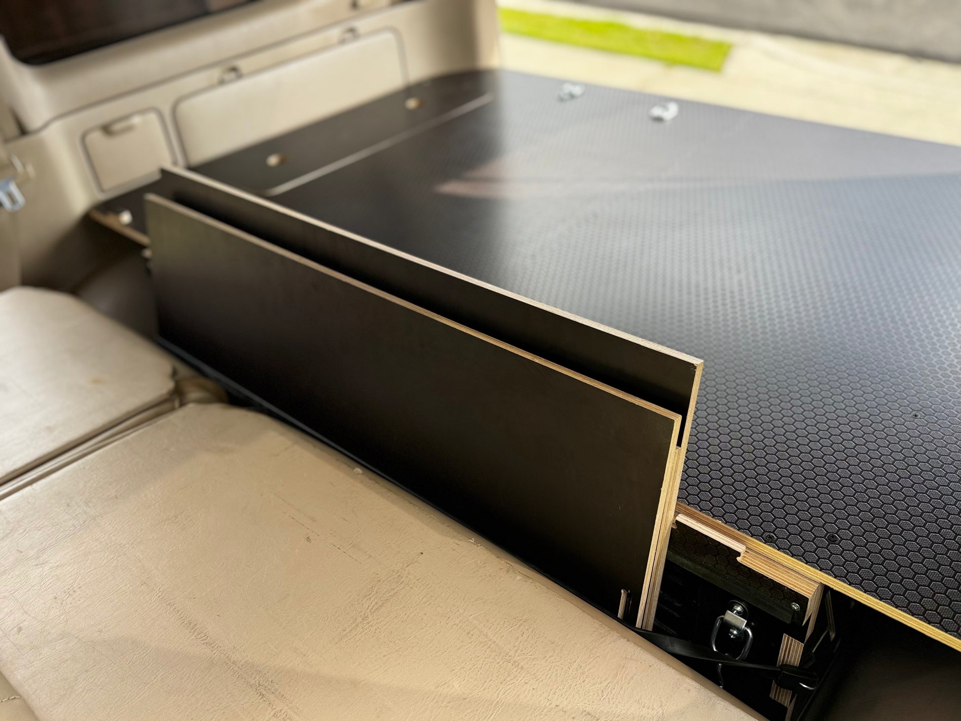 Close-up of a custom wood vehicle drawer system with black hexagonal panel in SUV cargo area