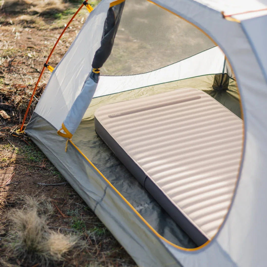 Inflatable camping mattress inside a pitched tent on outdoor ground