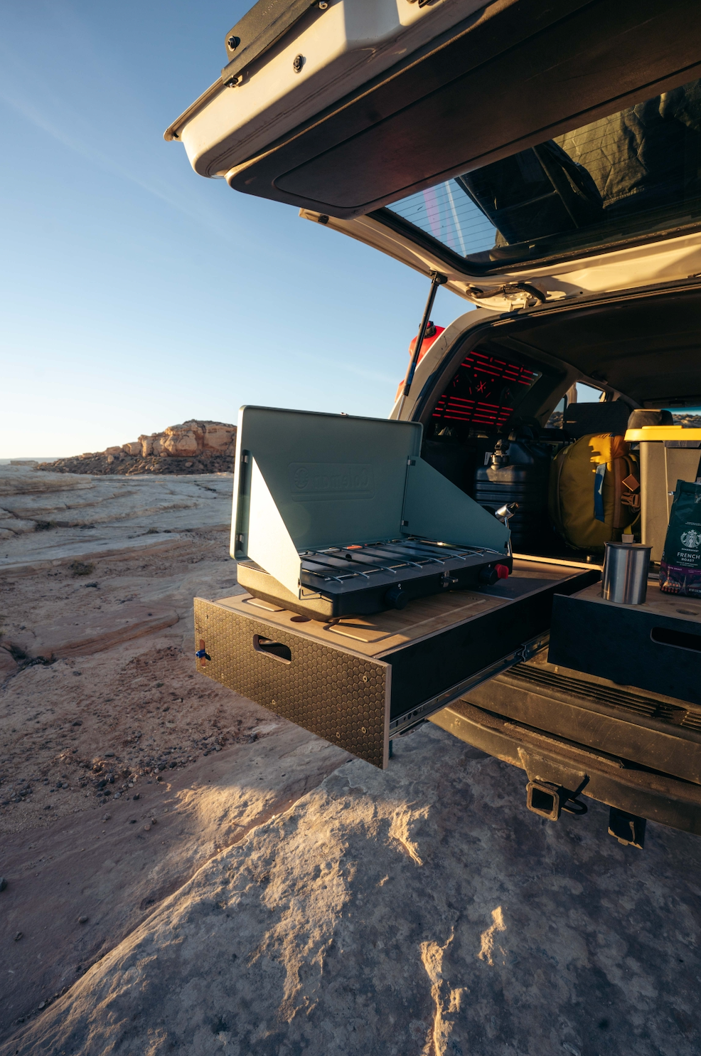 Vehicle drawer storage system with camp stove set up at a scenic outdoor location