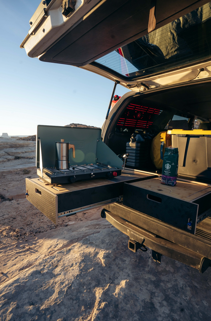 Vehicle with rear drawer storage system and pull-out camping kitchen on desert terrain