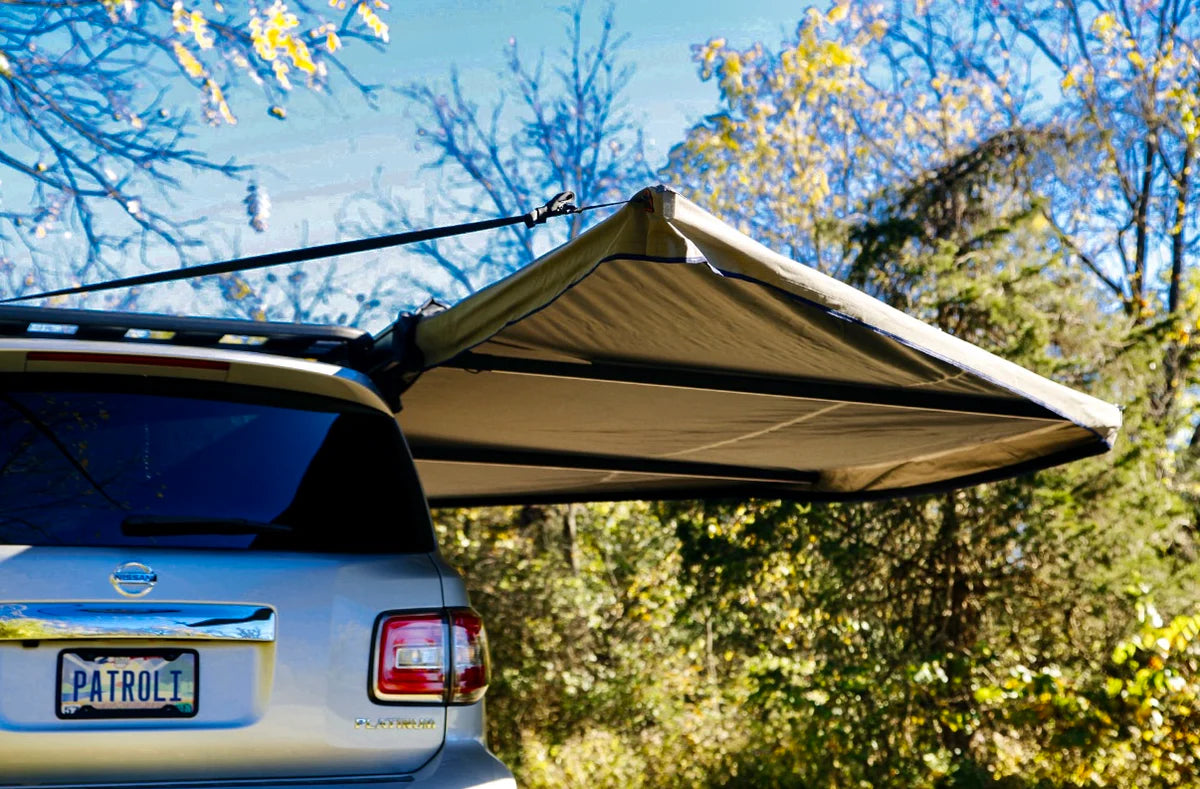 SUV with rear-mounted awning deployed for outdoor vehicle storage and camping