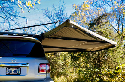 SUV with rear-mounted awning deployed for outdoor vehicle storage and camping