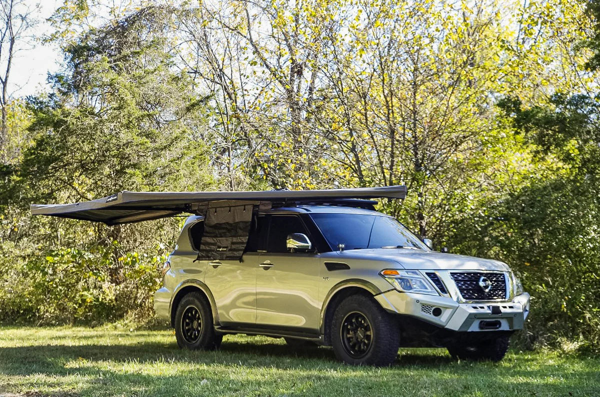 SUV equipped with a roof awning storage solution, parked outdoors in a wooded area.